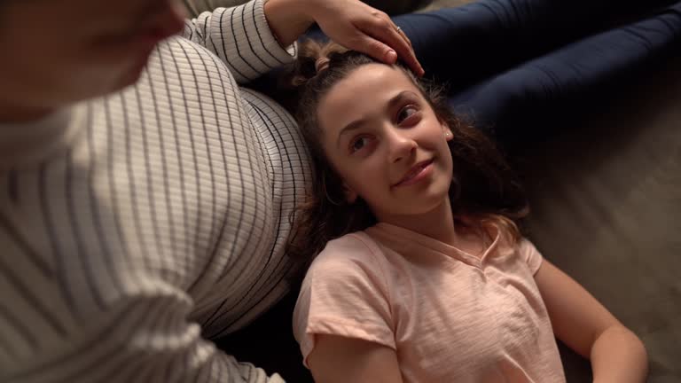 Daughter laying on mother's lap at home