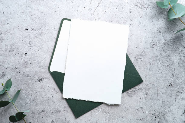 istock RSVP, wedding invitation mockup. Blank paper card with green envelope and eucalyptus on stone table top view. 1368485034