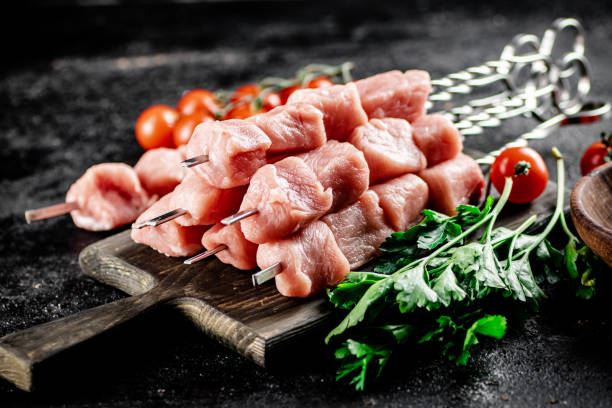 istock Pork kebab raw on a cutting board with tomatoes and parsley. 1368489755