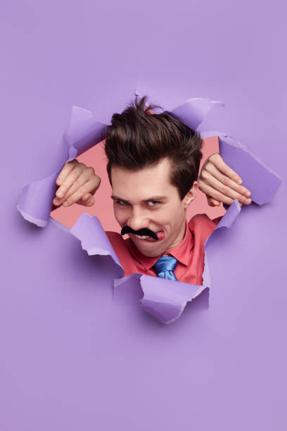 istock Funny seducer man peeking out of torn paper 1368491546