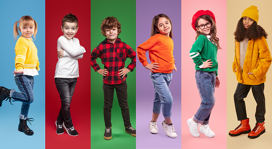 Set of diverse confident children in stylish casual clothes looking at camera while standing against vivid background in studio