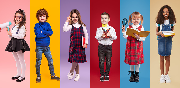 Set of multiracial happy girls and boys in trendy casual clothes with school supplies smiling at camera while standing against vibrant background in studio