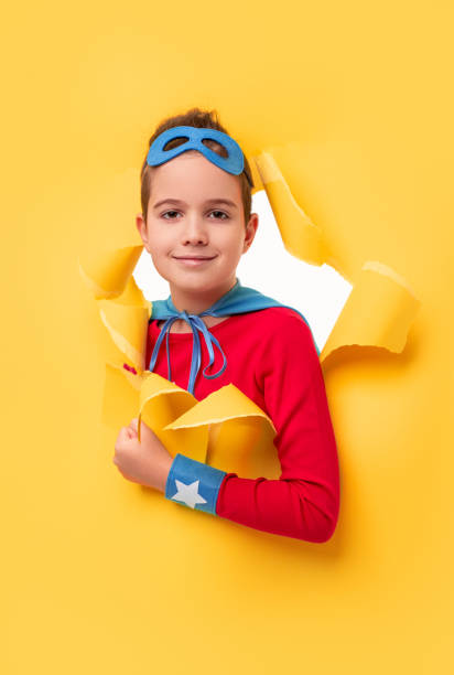 黄色い紙の穴から覗く小さなスーパーヒーロー - superhero child creativity little boys ストックフォトと画像