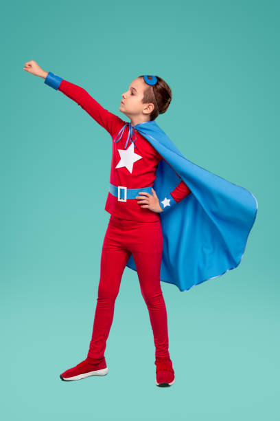 istock Little brave superhero kid standing with raised arm in studio 1368491595