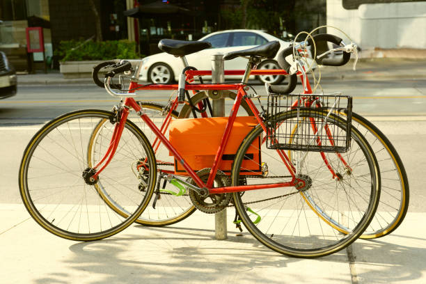 Two red locked old road bikes with drop handlebars on circle metal bicycle rack on city street side walk