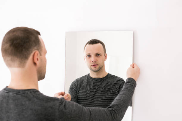 istock A man standing in front of a white wall with a mirror 1368494310