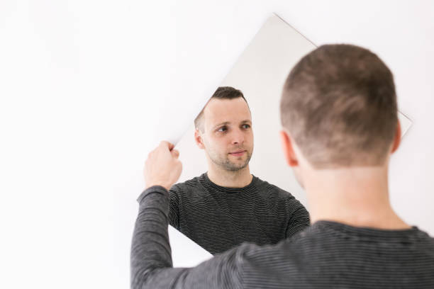 istock Young man standing with a mirror in his hands 1368494311