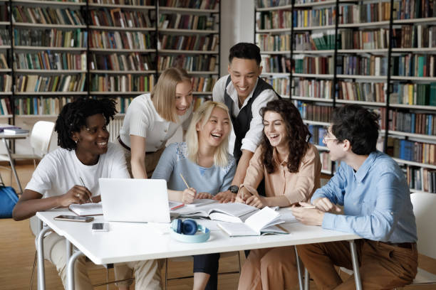 istock Happy mixed race group of students working in library together 1368496798