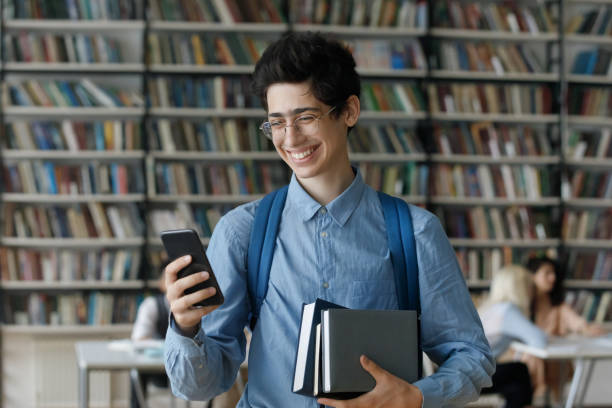 istock Excited young student boy in glasses holding stacked books 1368496815