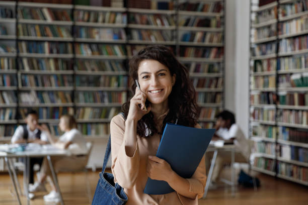 istock Happy college student talking on mobile phone in university library 1368496818