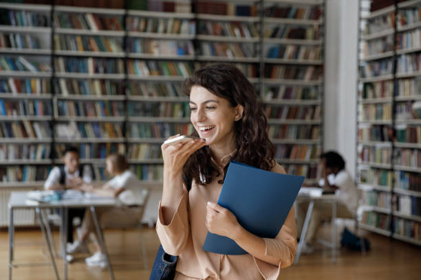 istock Cheerful happy Latin student recording voice message in library 1368496828