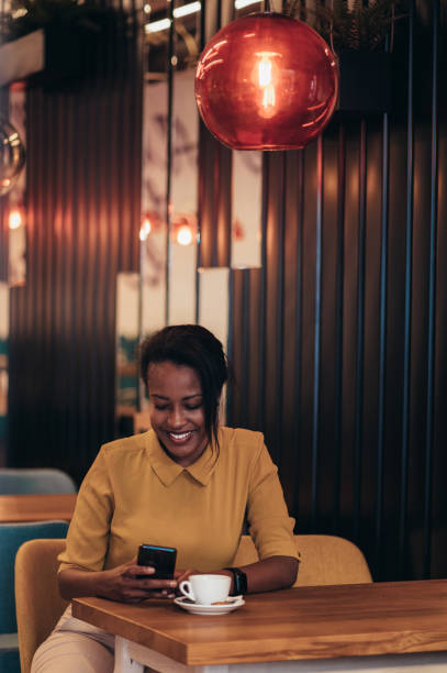 istock African american woman using a smartphone and drinking coffee while sitting in a cafe 1368498168