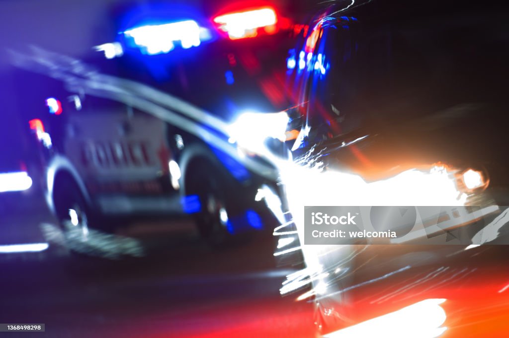 Hot Pursuit Police Traffic Chase at Night Hot Pursuit Police Traffic Chase at Night. Police Cruiser Next to Running Out DUI Driver Conceptual Photo with Motion Blurs. Police Enforcement Theme. Driving Under The Influence Stock Photo