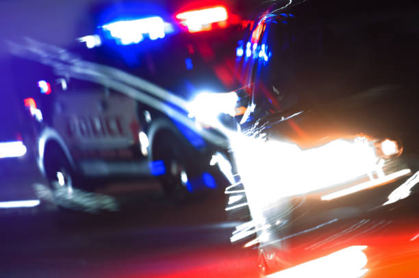Hot Pursuit Police Traffic Chase at Night Hot Pursuit Police Traffic Chase at Night. Police Cruiser Next to Running Out DUI Driver Conceptual Photo with Motion Blurs. Police Enforcement Theme. chasing photos stock pictures, royalty-free photos & images