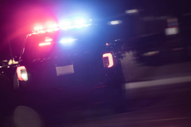 istock Police Cruiser with Flashing Lights in Night Time Action 1368498363