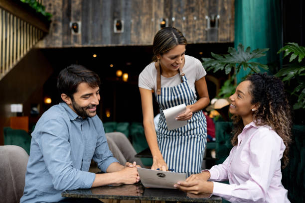Clients at a restaurant asking questions about the menu to the waitress