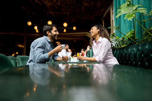 Happy Latin American couple having fun eating together at a restaurant and talking - lifestyle concepts