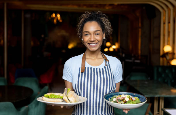istock Happy waitress serving food while working at a restaurant 1368500072
