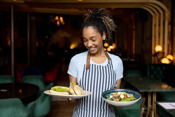 istock Beautiful waitress serving food at a restaurant 1368500075