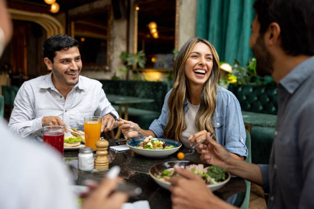 feliz grupo de amigos almorzando juntos en un restaurante - restaurante fotografías e imágenes de stock