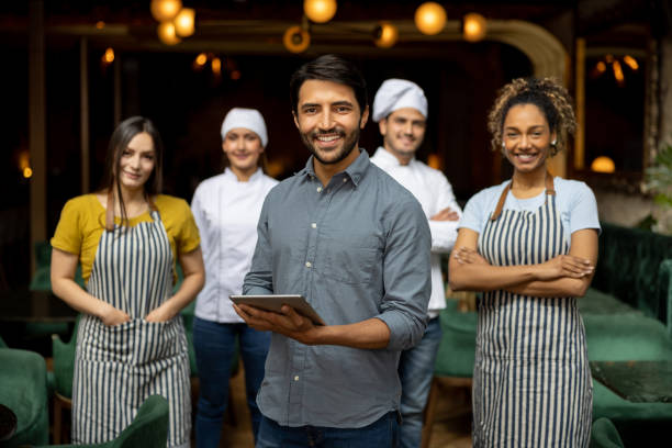 porträt eines geschäftsinhabers, der mit seinen mitarbeitern in einem restaurant lächelt - restaurant waiter food serving stock-fotos und bilder