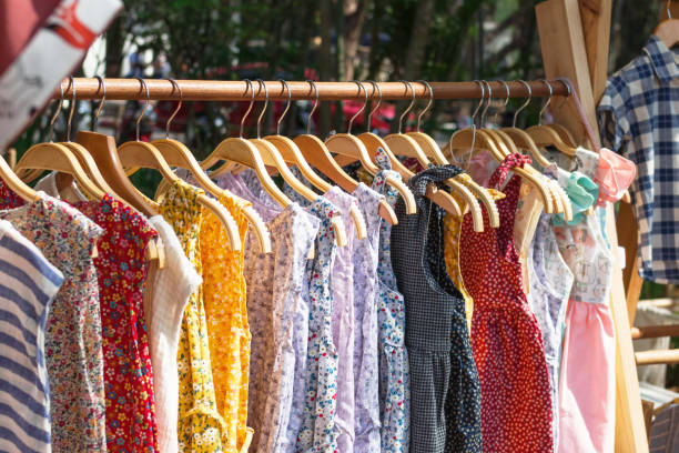 Wooden clothes racks with hangers and with colorful dresses. Showcase with clothes on street market. Wooden clothes racks with hangers and with colorful dresses. Showcase with clothes on street market. sundress stock pictures, royalty-free photos & images