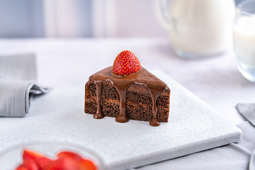 slices of homemade chocolate cake with fresh fruit on a black plate, top view
