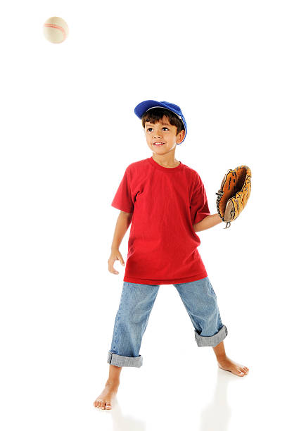 A barefoot preschooler ready to catch a coming ball in his mitt.  Motion blur on the ball. On a white background.