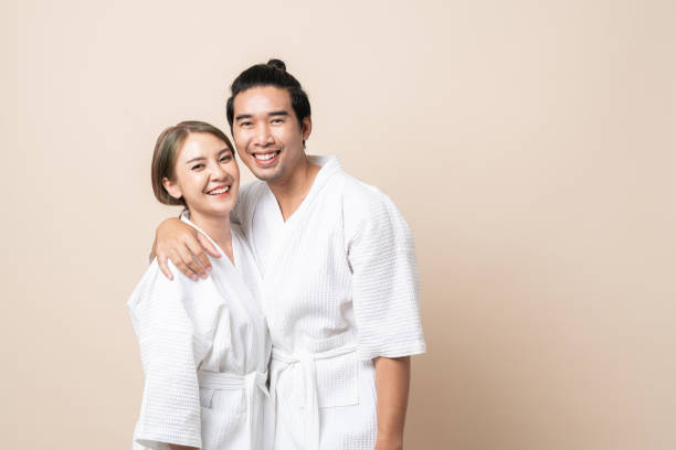 Asian couple in bathrobe happy smile together on brown isolated background. stock photo