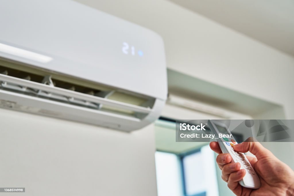 Hand adjusting temperature on air conditioner Hand adjusting temperature on air conditioner with remote control, Working air conditioner for comfort temperature in home at hot summer Air Conditioner Stock Photo