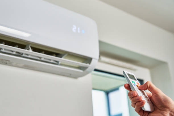 Hand adjusting temperature on air conditioner Hand adjusting temperature on air conditioner with remote control, Working air conditioner for comfort temperature in home at hot summer aircon stock pictures, royalty-free photos & images