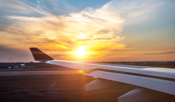 airplane wing at sunset. travel, air travel. flight during dawn, a beautiful view in window of an airplane with bright sky - wing airplane window sunset imagens e fotografias de stock