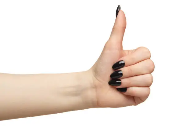 Female hands with black nails manicure with thumb up.  Isolated on white background.