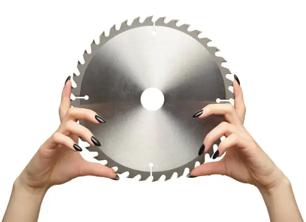 Female hands with black nails manicure with circular saw blade. Isolated on white background.
