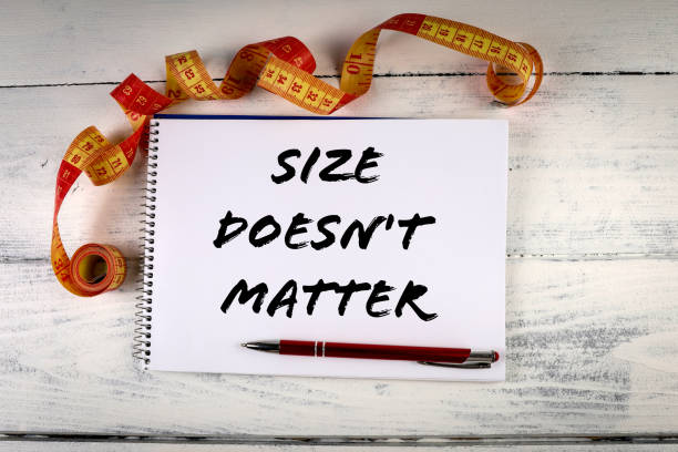 istock Size doesn't matter. Tape measure and notepad with pen on a white wooden background 1368518413
