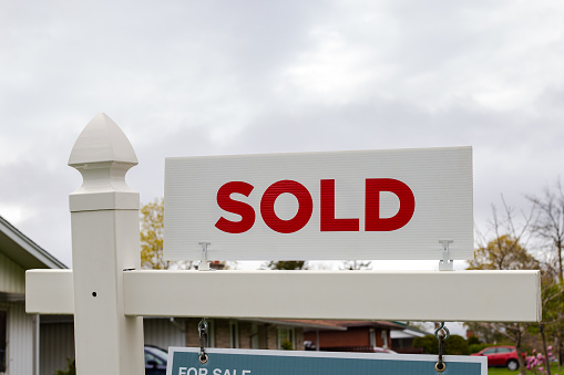 Sold sign in front of a house in a residential neighborhood