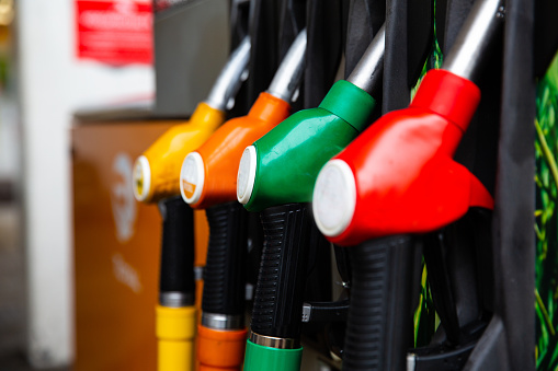 Detail of a petrol pump in a petrol station.Close up on fuel nozzle in oil dispenser with gasoline and diesel in service gas station. Blue, green, red, golden colors.