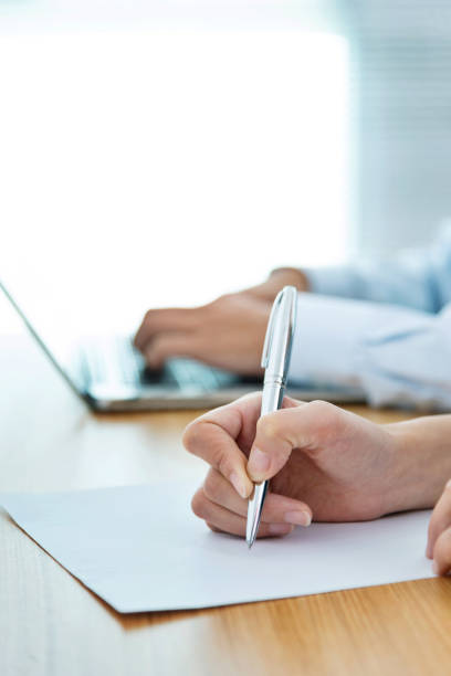 Business people writing on paper in office stock photo