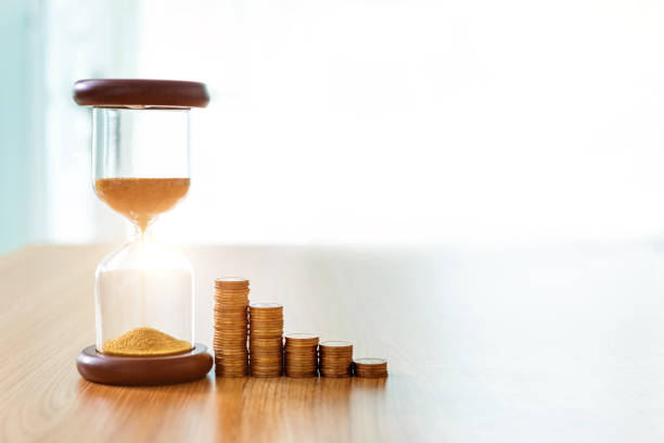 istock Hourglass and coins on wooden table 1368525709