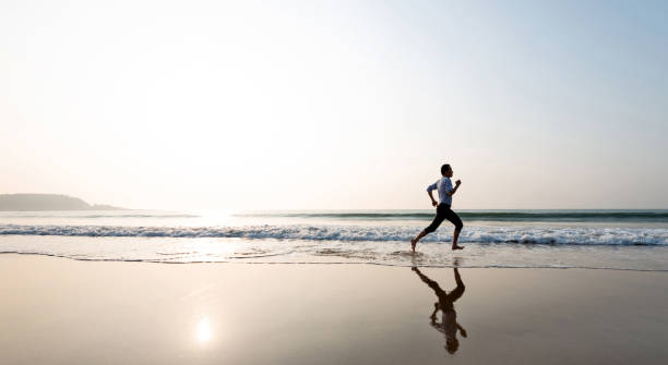 istock Man jogging on the beach at sunset 1368525762