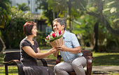 アジアの中年男性はバレンタインの日に彼の妻にバラを与える