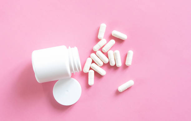 istock Close up white pills and capsules on pink background with copy space. Focus on foreground, soft bokeh. Pharmacy drugstore concept. 1368531468
