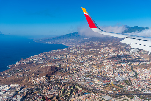 Santa Cruz de Tenerife, Spain - August 2, 2021: View of the wing of an Iberia Airline Airplane flying before landing in Santa Cruz de Tenerife in the Canary Islands