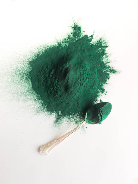 monte de pó de espirulina e uma colher no fundo branco - spirulina bacterium seaweed food clipping path - fotografias e filmes do acervo