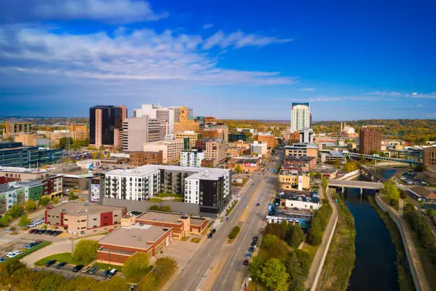 Downtown Rochester skyline aerial view during early Autumn, with a blue skyline with clouds in the background.