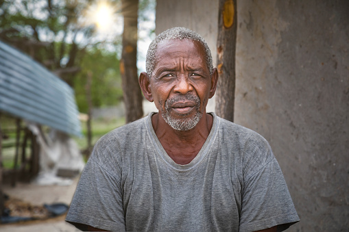 old african man in front of the house in an african village
