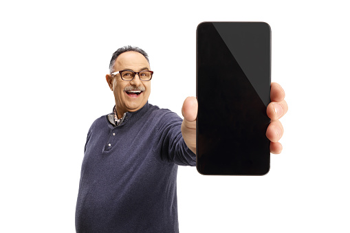 Smiling mature casual man showing a mobile phone in front of camera isolated on white background