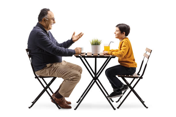 Grandfather sitting at a cafe table and talking to a grandson isolated on white background