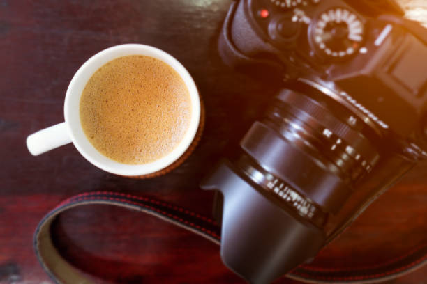 istock Cup of coffee and camera on a wood table. Top view. 1368544847