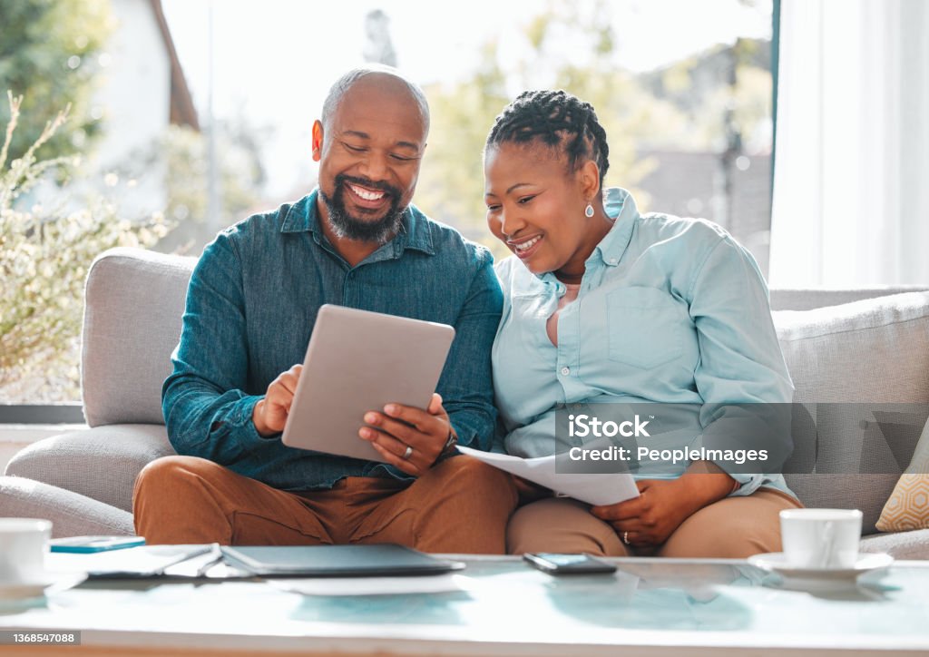 Shot of a mature couple looking through their bills while using a digital tablet The days are best spent with you Couple - Relationship Stock Photo
